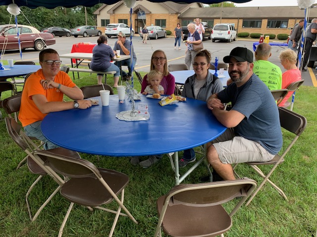 Members sitting at a picnic table enjoying refreshments