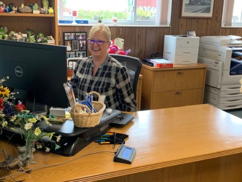 Employee sitting at her computer smiling at the camera