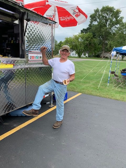 Member picking up their hot dog from the hot dog stand